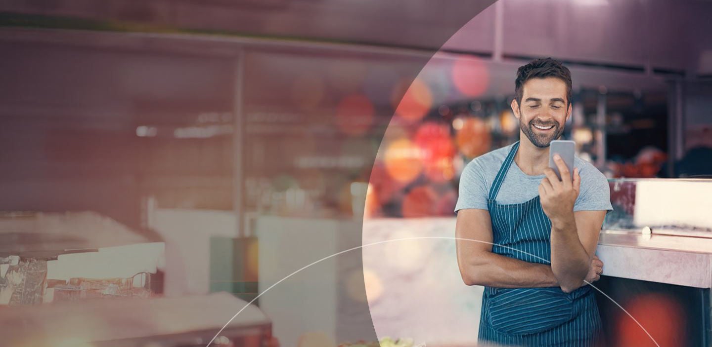 man in apron looking at the cell phone.