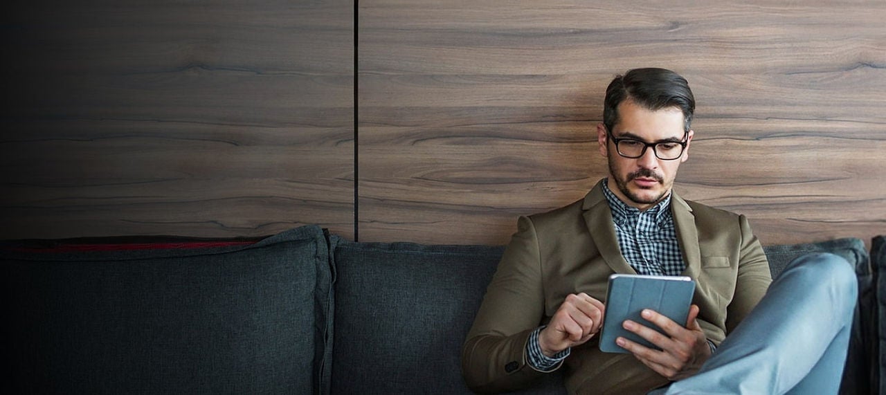 man using tablet on couch