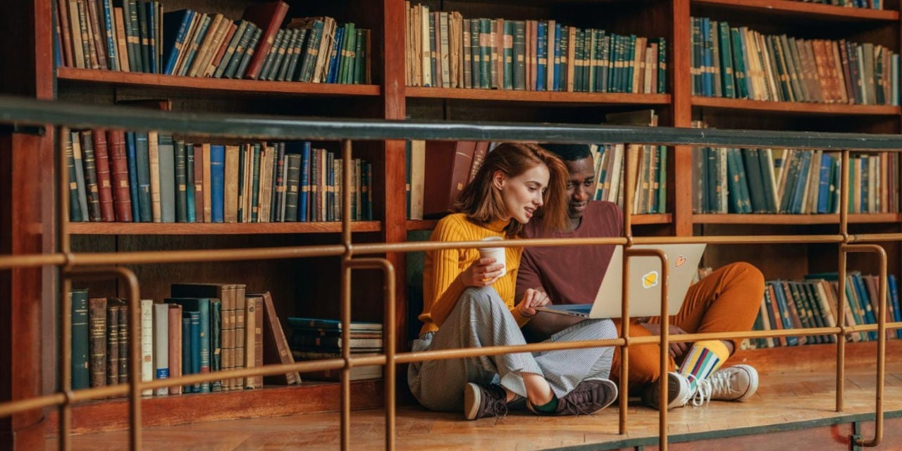 Muškarac i žena gledaju u računar u biblioteci