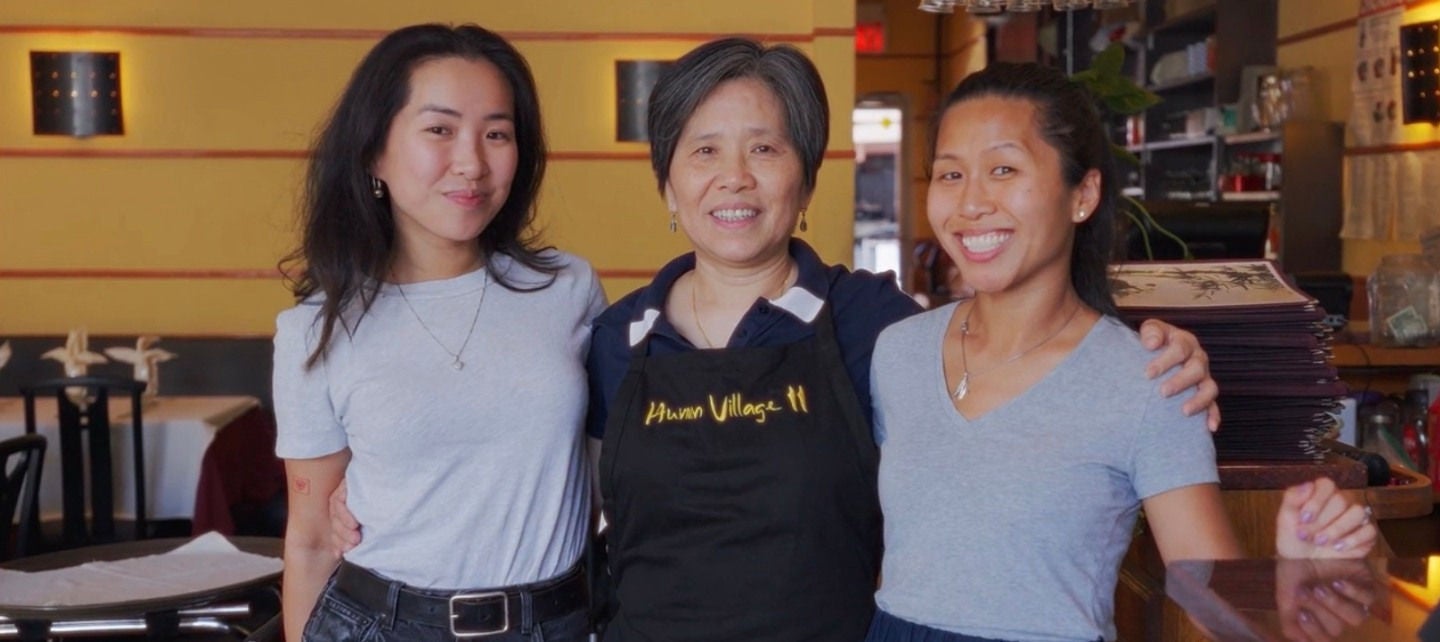 Jennifer, Gloria and Jessica Jeng with their arms around each other in Gloria's restaurant. 