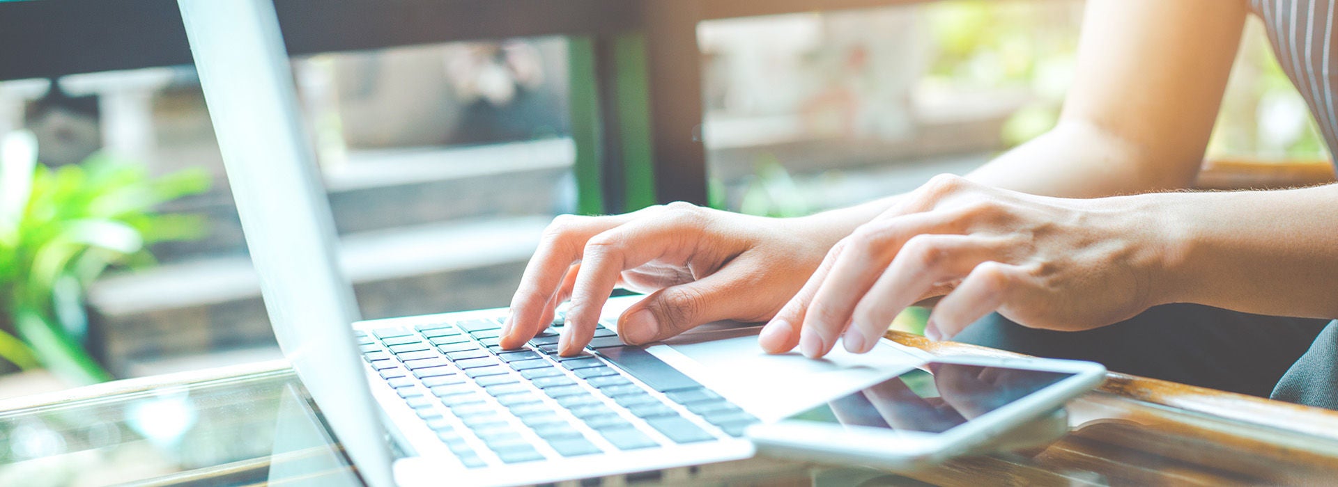 Osoba pracujúca s počítačom a mobilným telefónom