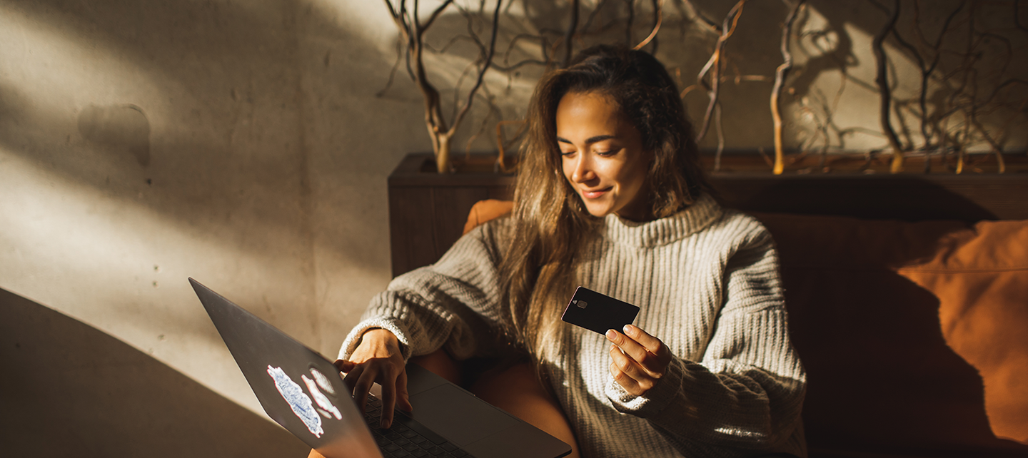 Woman shopping on her laptop with her card in hand