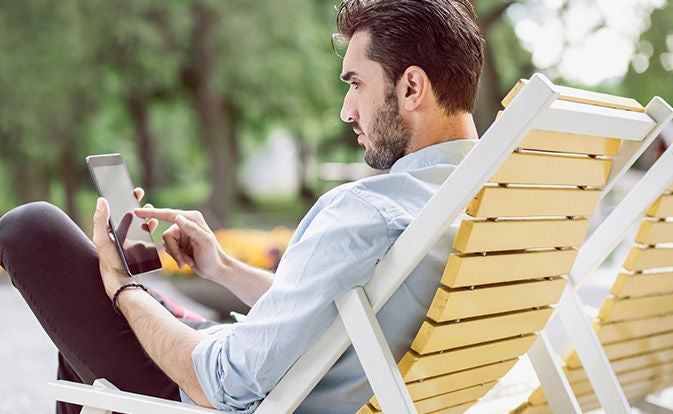 Man relaxing outdoors while using a mobile phone.