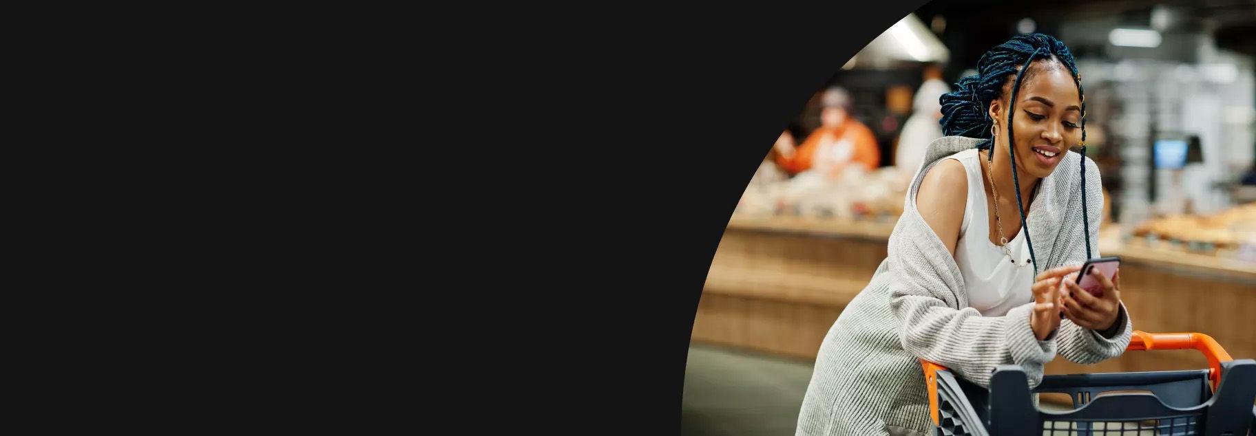 Woman leaning over he shopping cart checking her phone