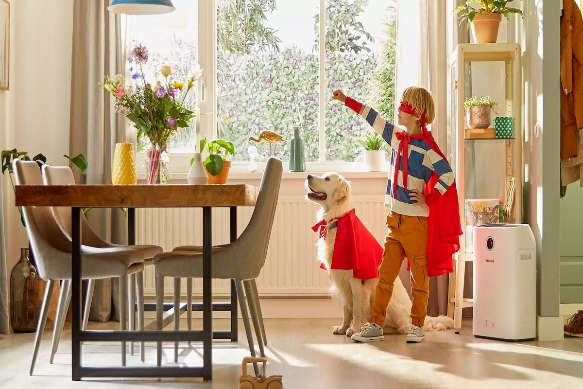 Kind und Hund mit rotem Superheldenumhang