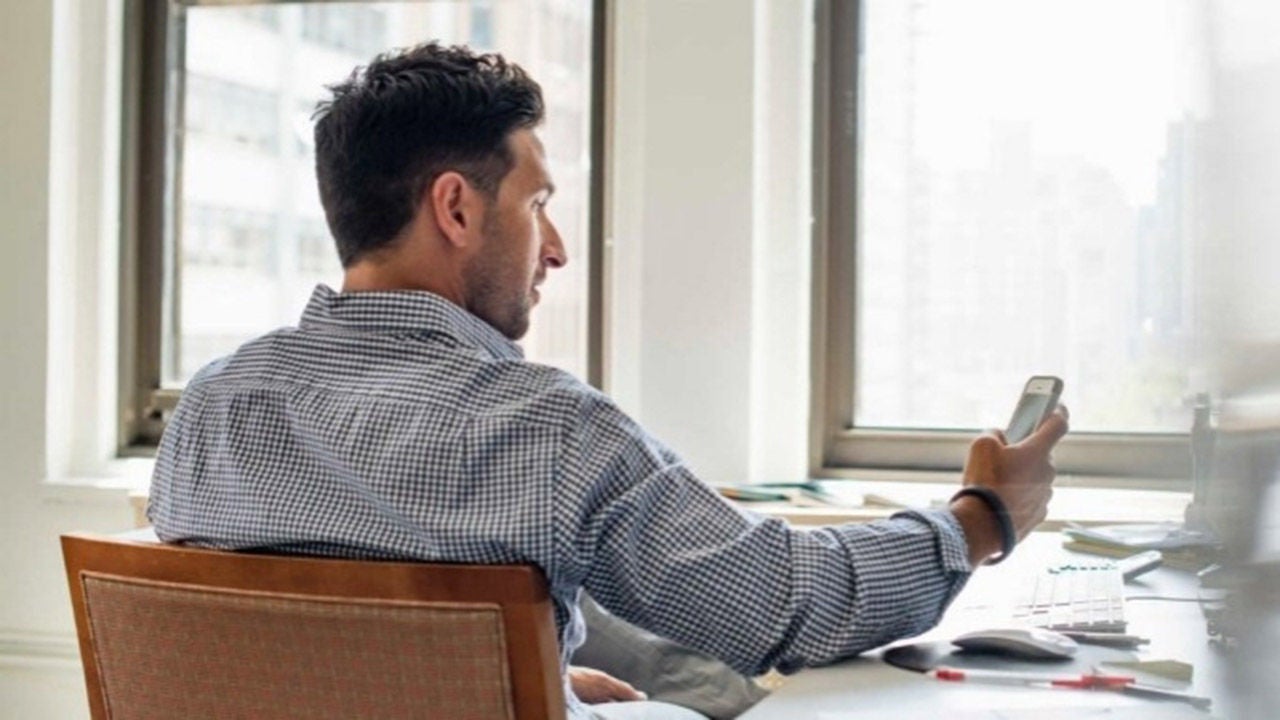 man using phone by windows