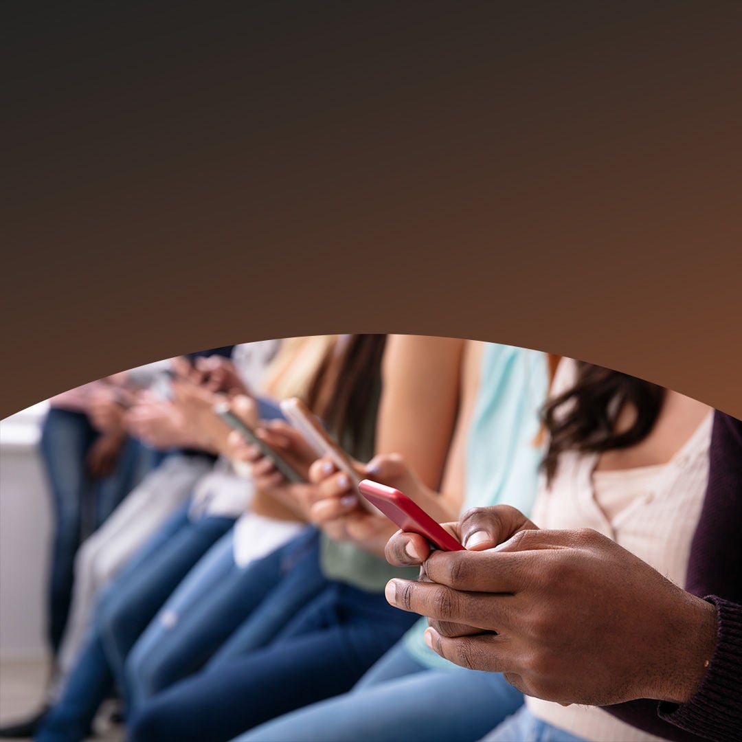 Fila de jóvenes usando teléfonos celulares.