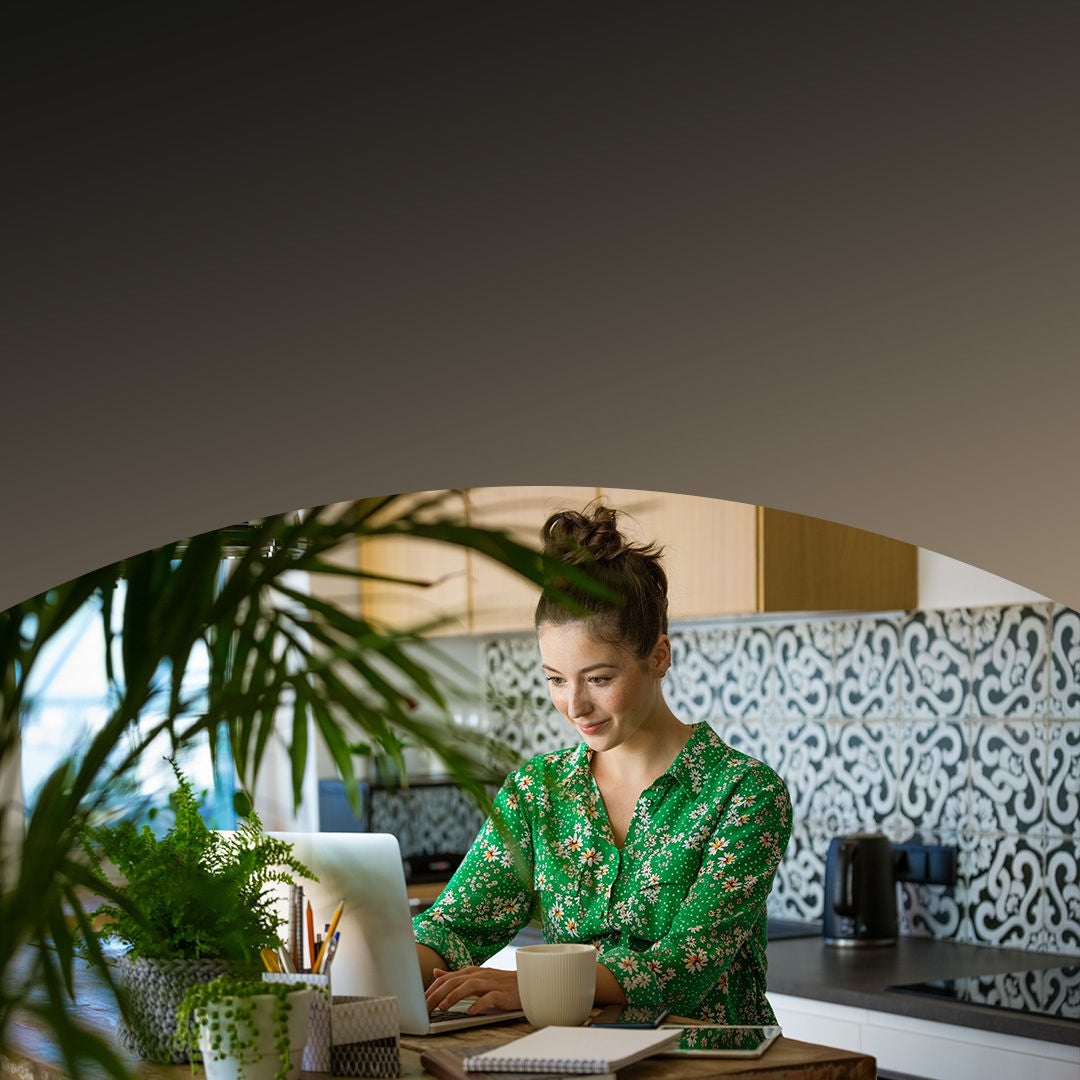Young woman using laptop at home kitchen.