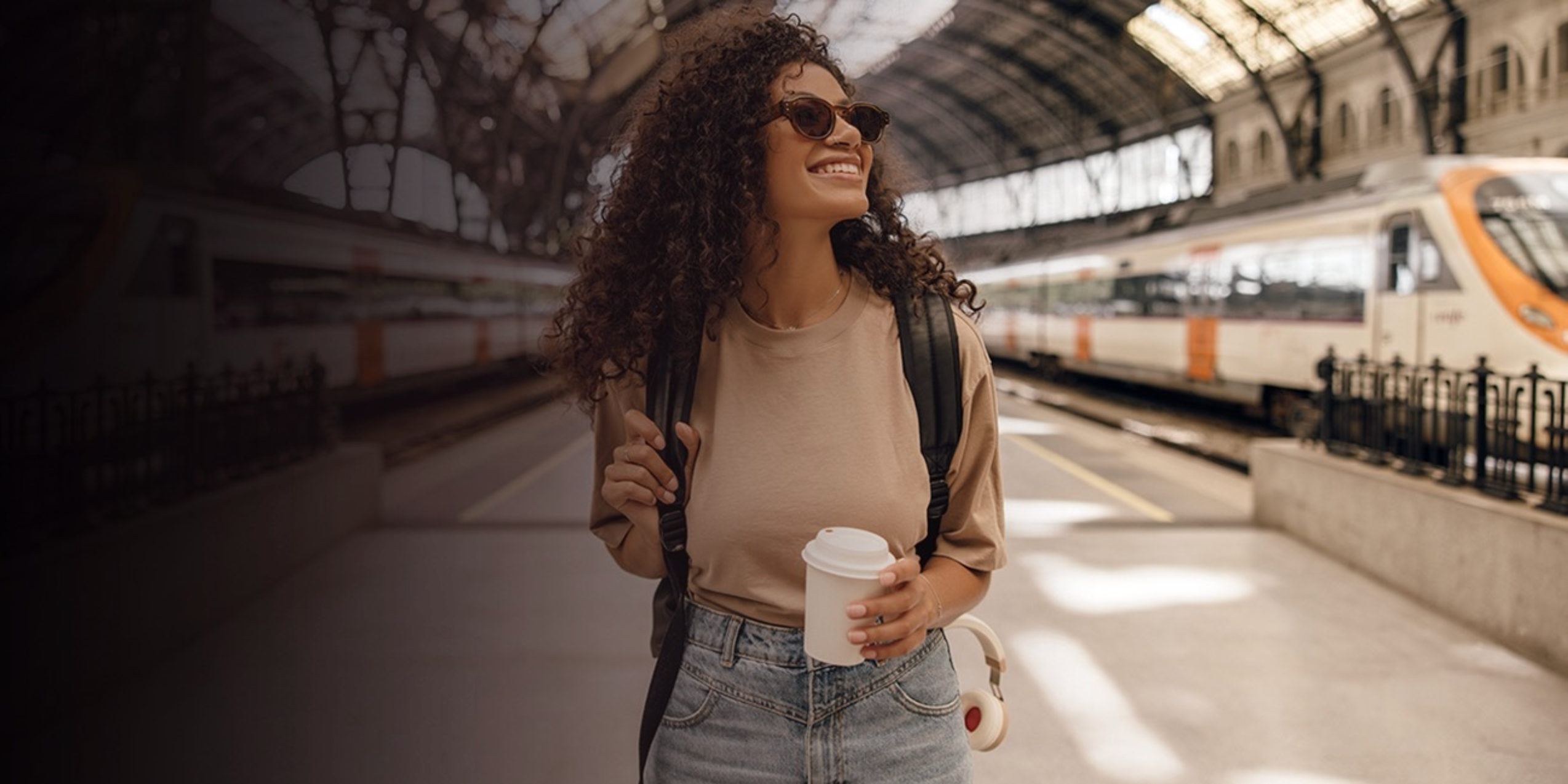 Girl on train station smiling with coffee