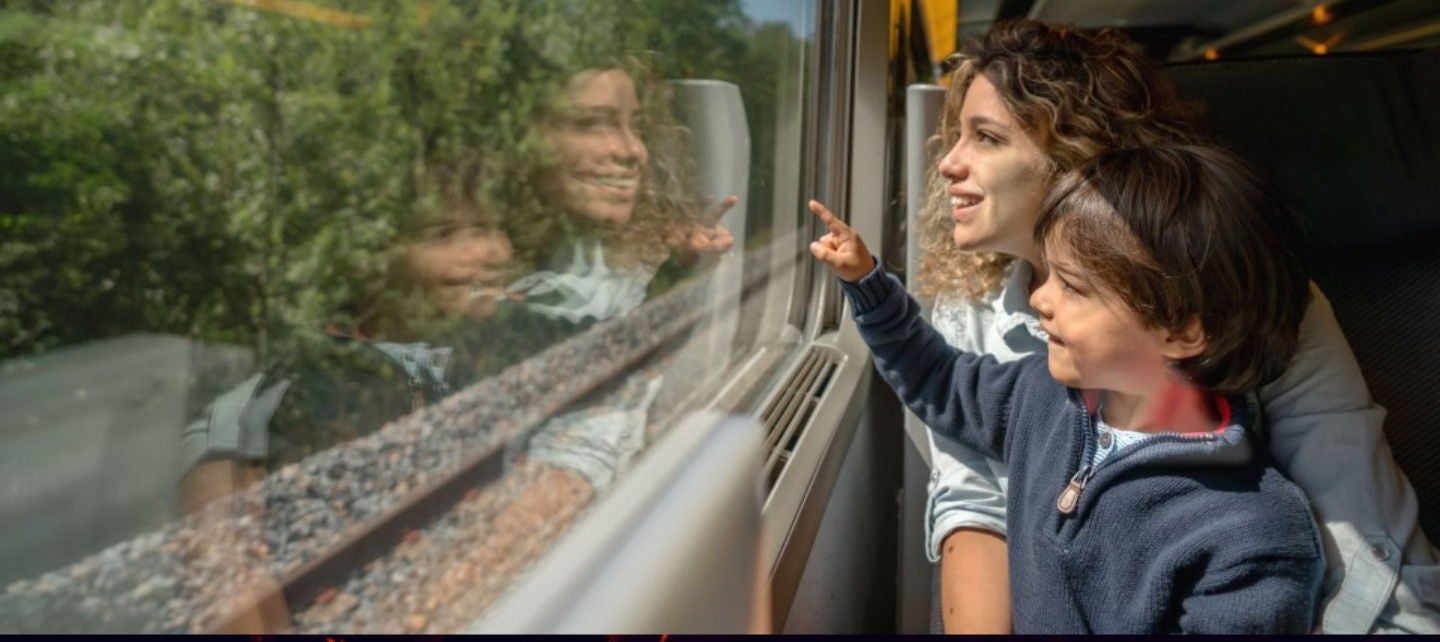 A woman and her son look out a train window.