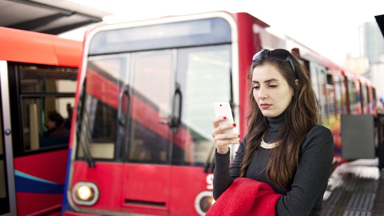 Woman looking at phone at bus stop.