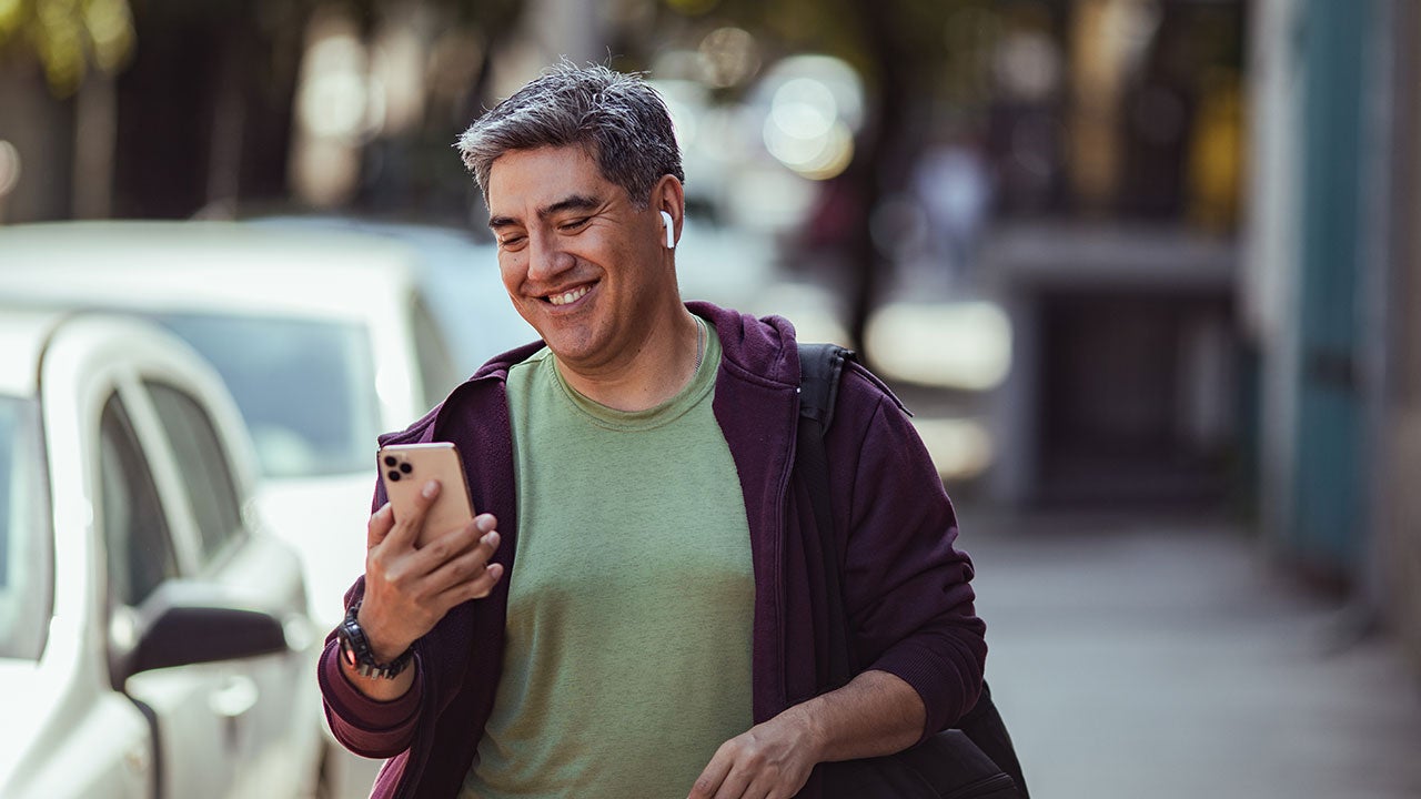 Man walking on a street with phone in his hands.