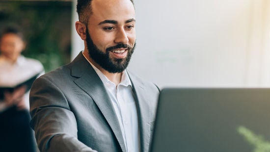 Bărbat care se uită la un computer zâmbind