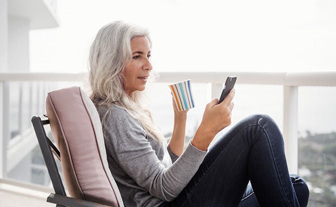 Mature woman using her phone while sitting on a chair