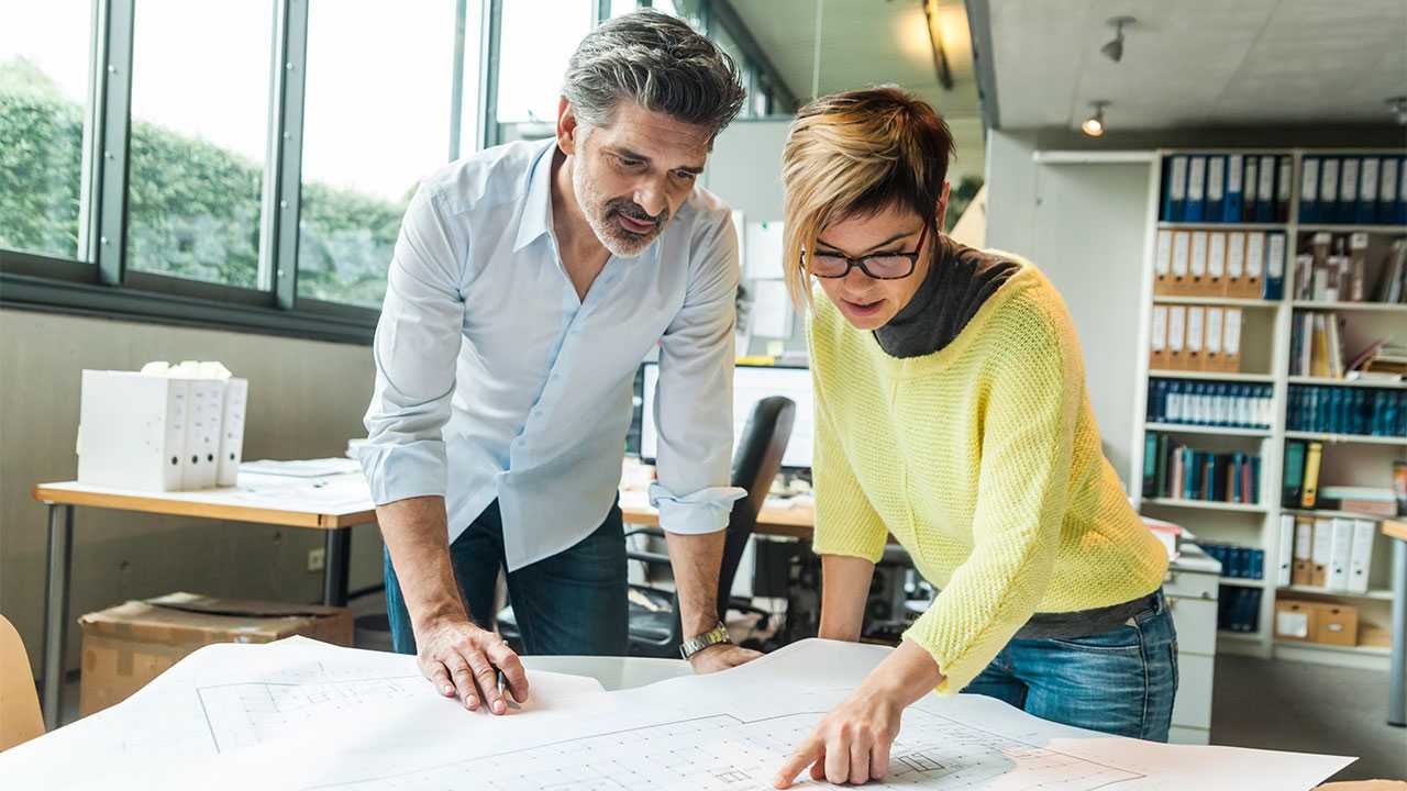 En mand og en kvinde arbejder sammen på et kontor og kigger på en plantegning.