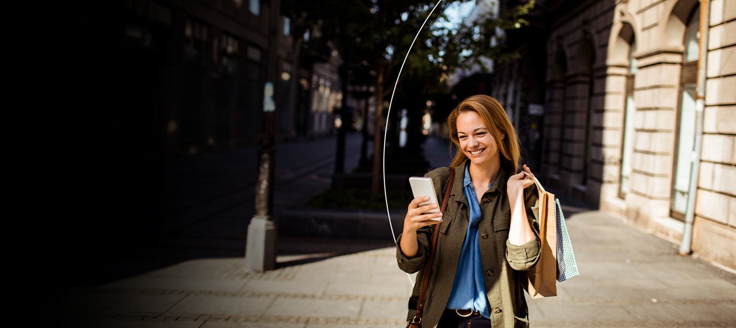 Kobieta przeglądająca telefon, wychodząc ze sklepu