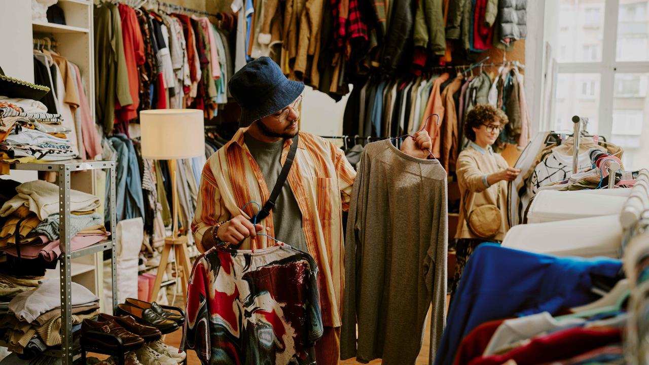A person looks at clothes on hangers in a vintage clothing store. 