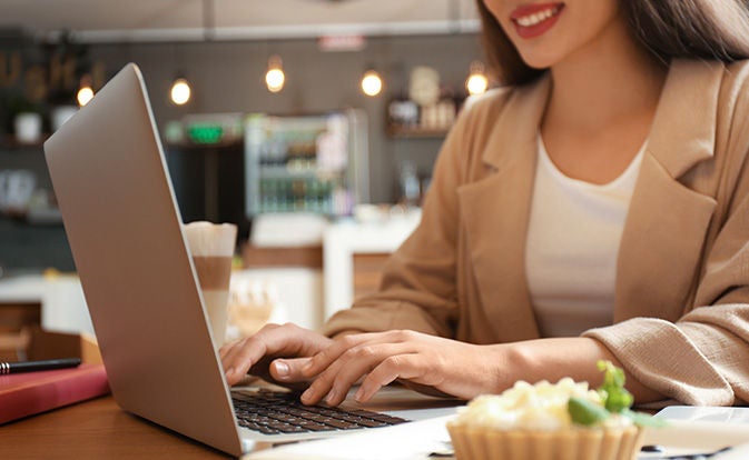 A woman focused on her laptop, typing intently with a thoughtful expression on her face.