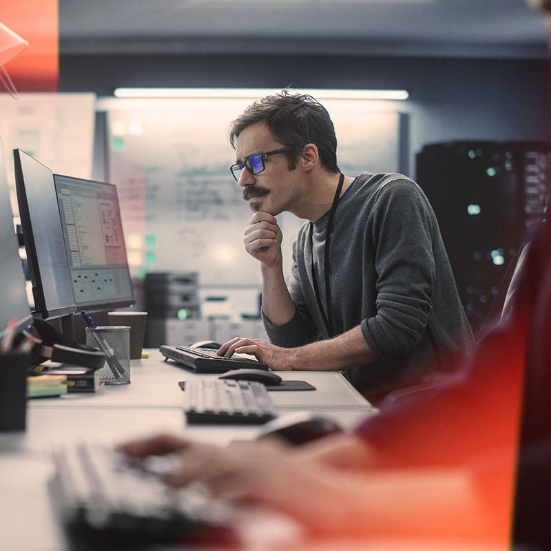 Man working on a laptop while sitting on a desk