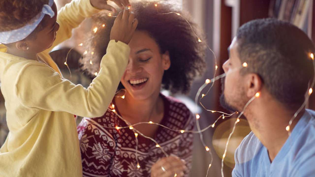 En familie er til en fest med julelys omkring sig.