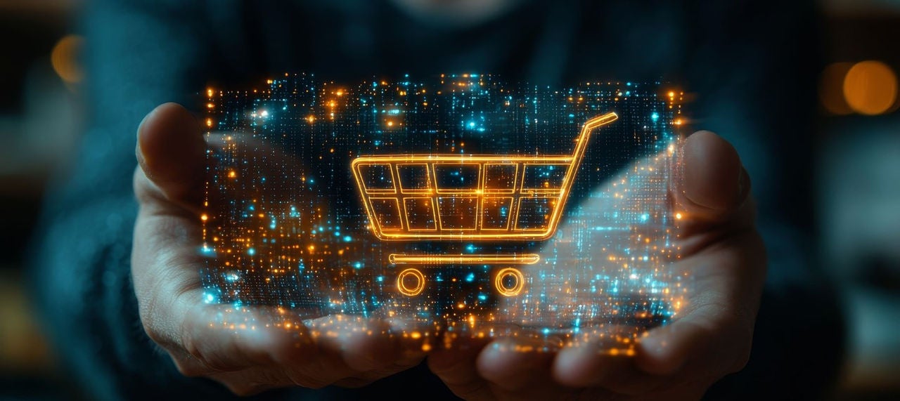 A shopping cart superimposed on top of a mobile phone screen with blue and orange  dots being held by a person's hands . 