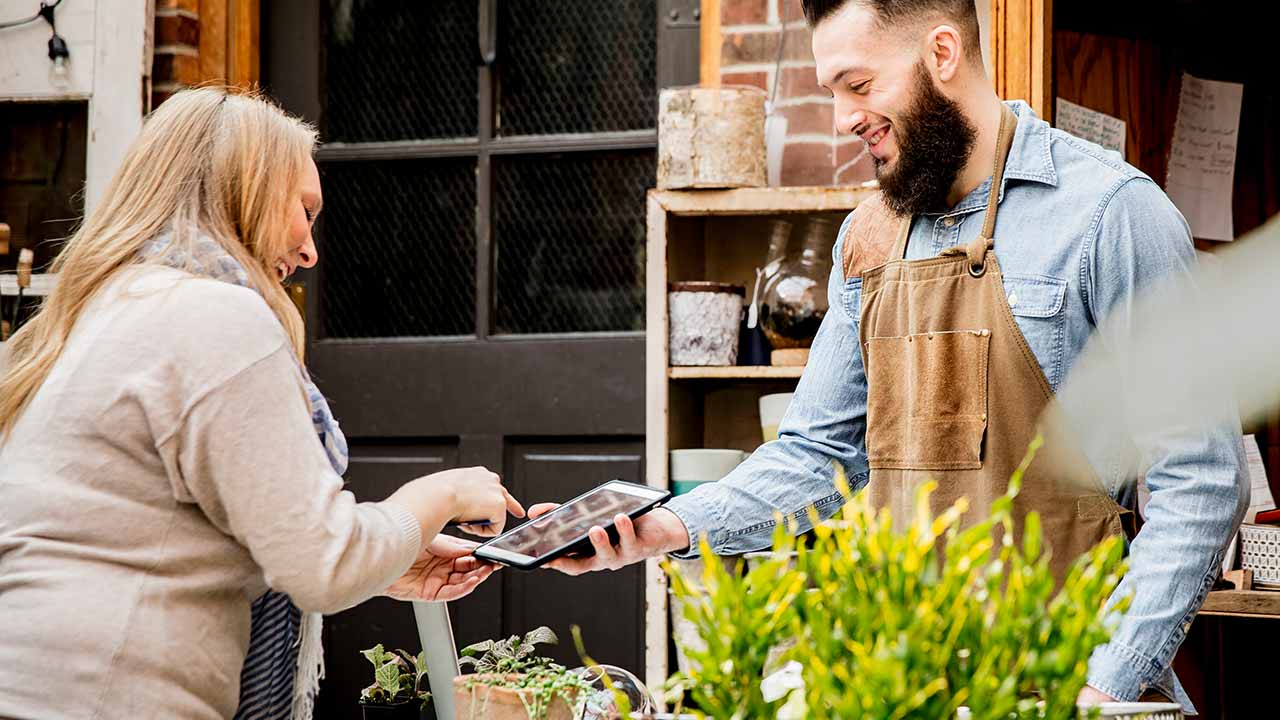un client effectue un achat en magasin avec une tablette.