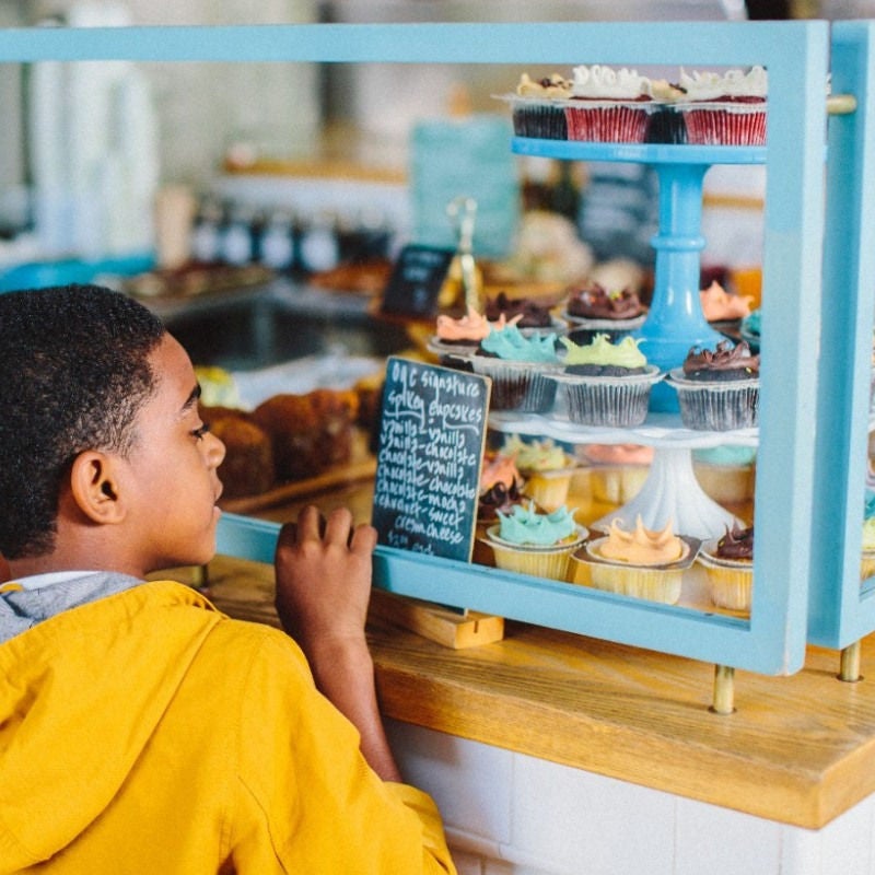 woman holding her hat facing a sunset