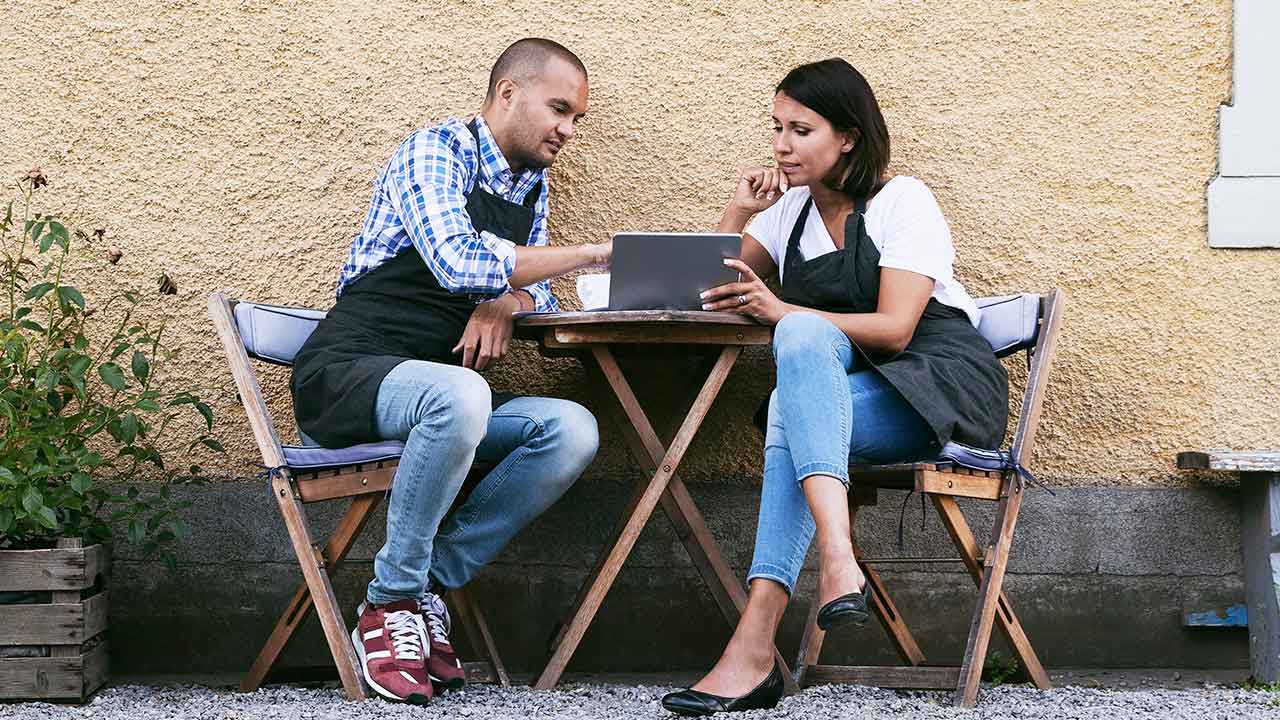 Small business owners looking at laptop outside.
