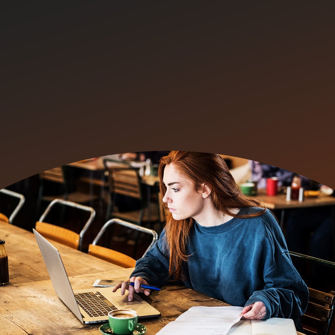 Woman working on laptop at restaurant.