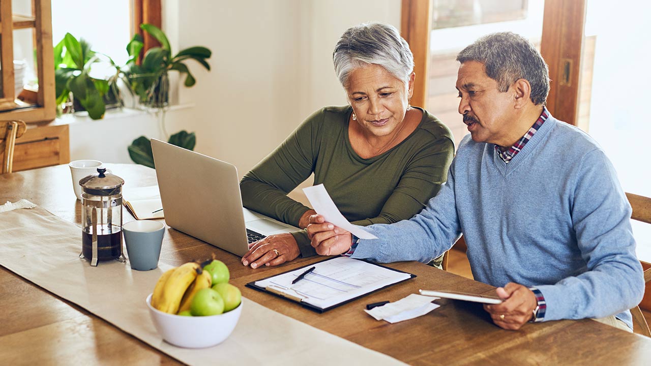 Senior couple with bills working on laptop.