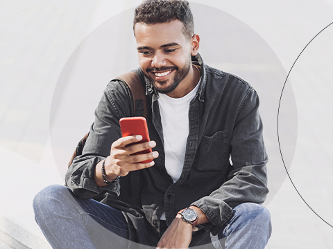 Man sitting outside smiling at phone