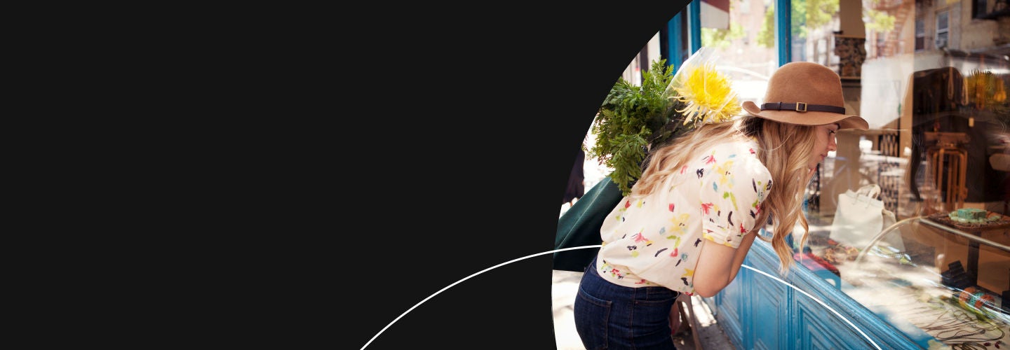 Frau beim Schaufensterbummel mit Blumen in der Hand