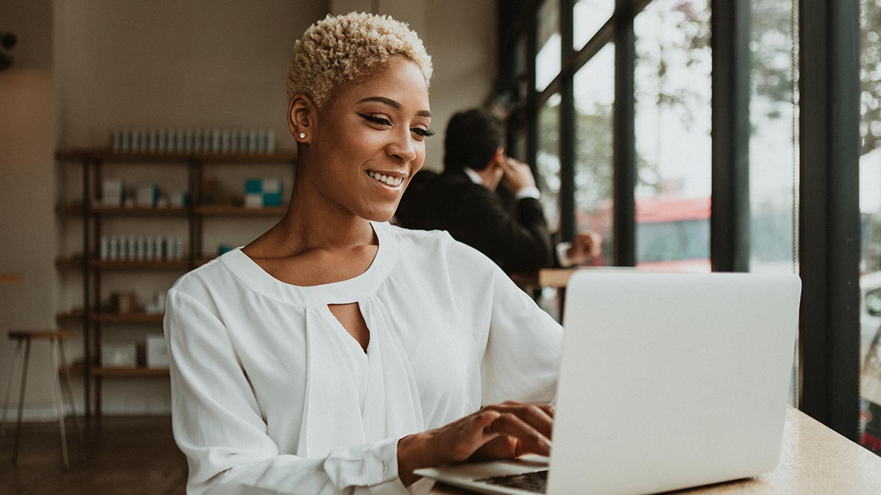 Stylish woman using laptop at salon.