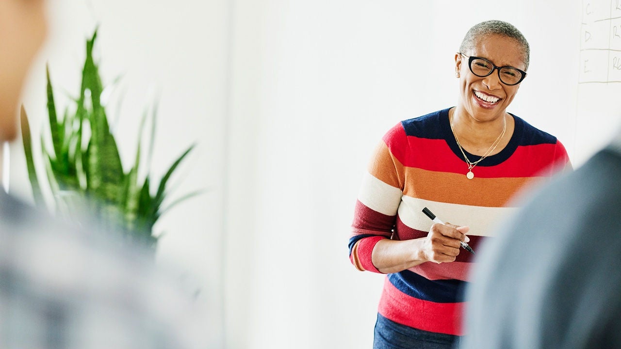 Woman wearing glasses working on a laptop in a bright office.