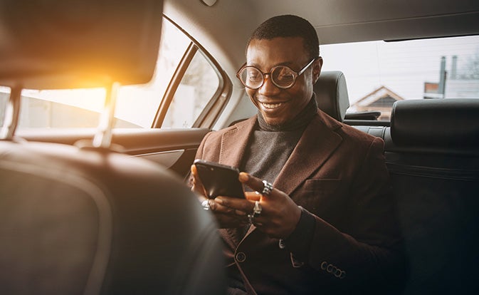 man using smartphone while sitting on backseat in a car.
