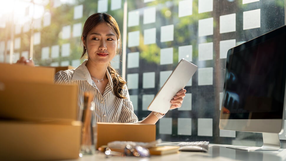 A woman sitting at a desk with a tablet