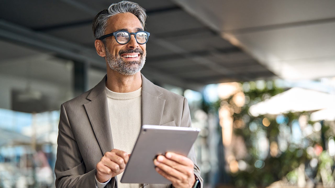 Confident small-business owner standing in a office with a tablet.