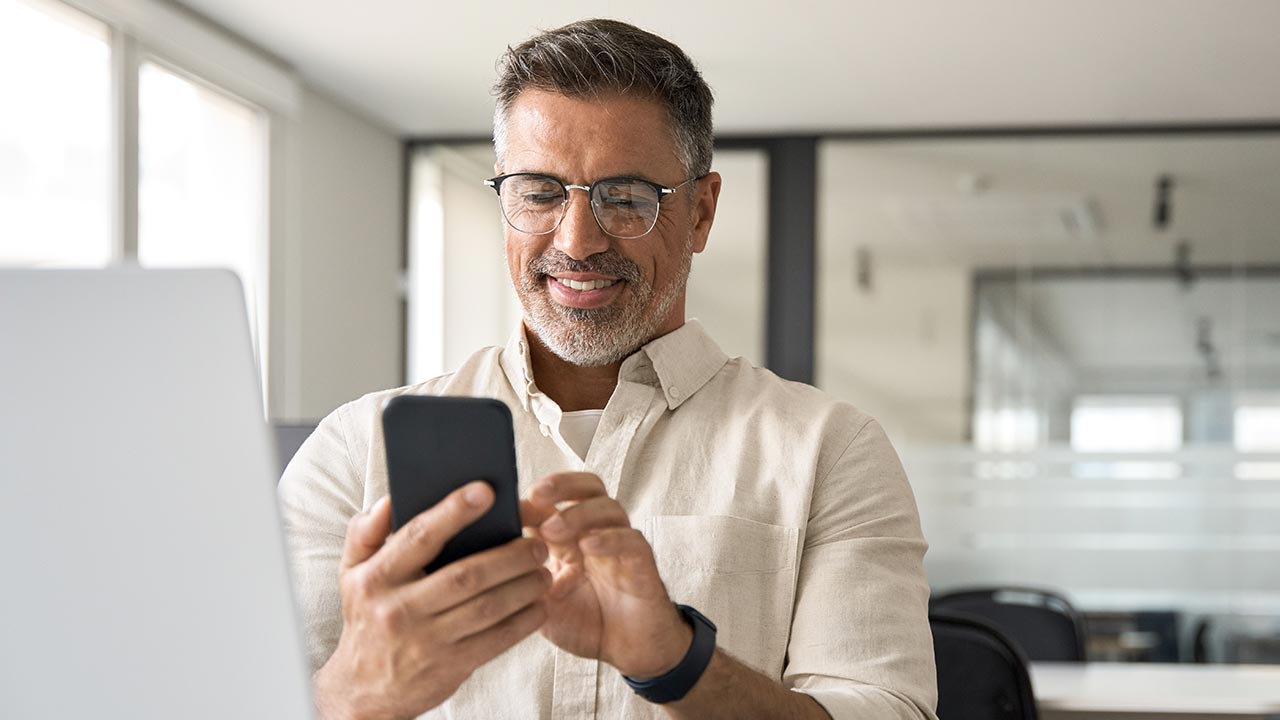 Professional man using phone and laptop.