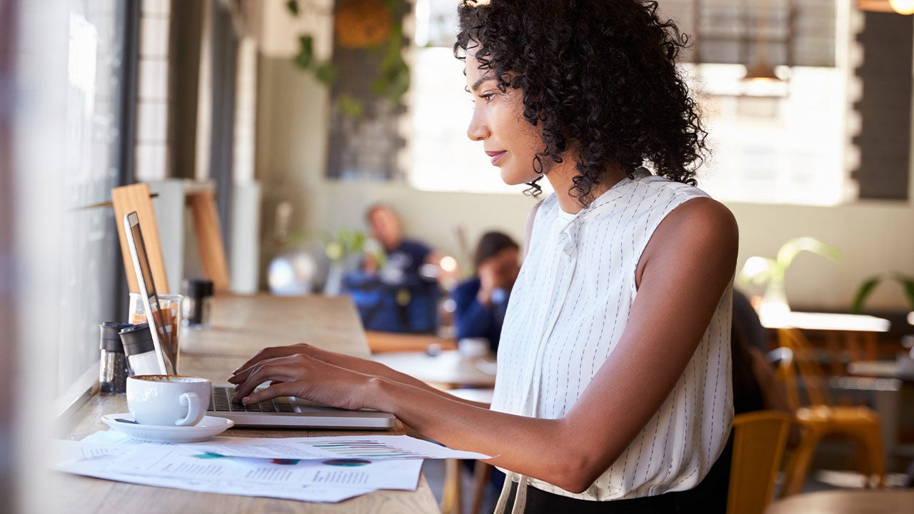 Businesswoman working on laptop by a window in coffee shop