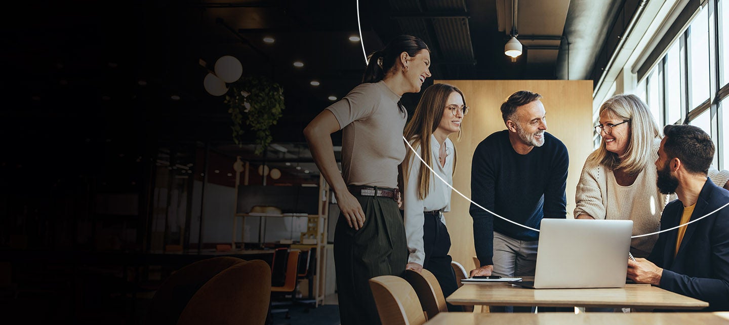 Grupa ljudi radi zajedno i sarađuje oko laptopa.