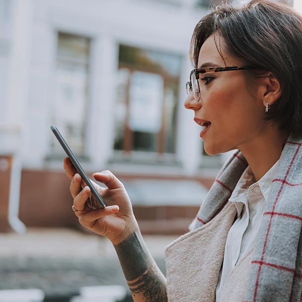 Profile of a woman with a phone outside.