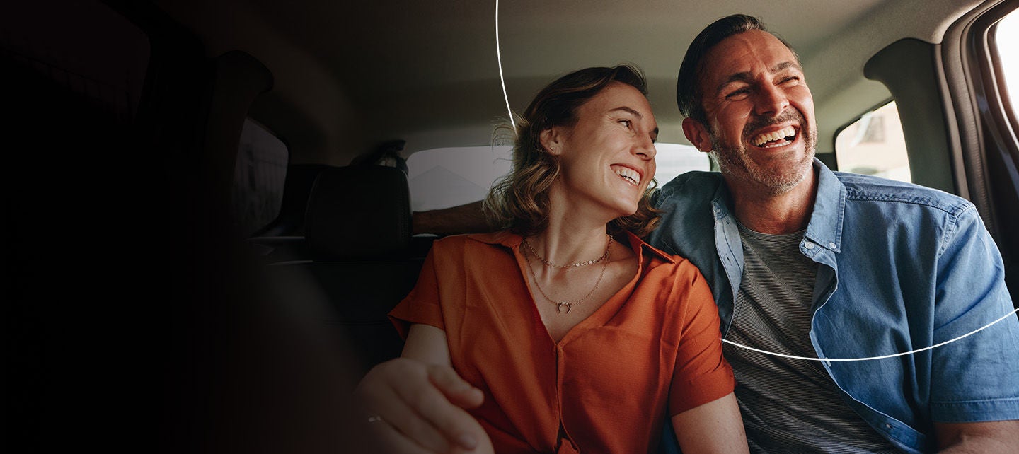 Par sjedi u automobilu i smiješi se. 