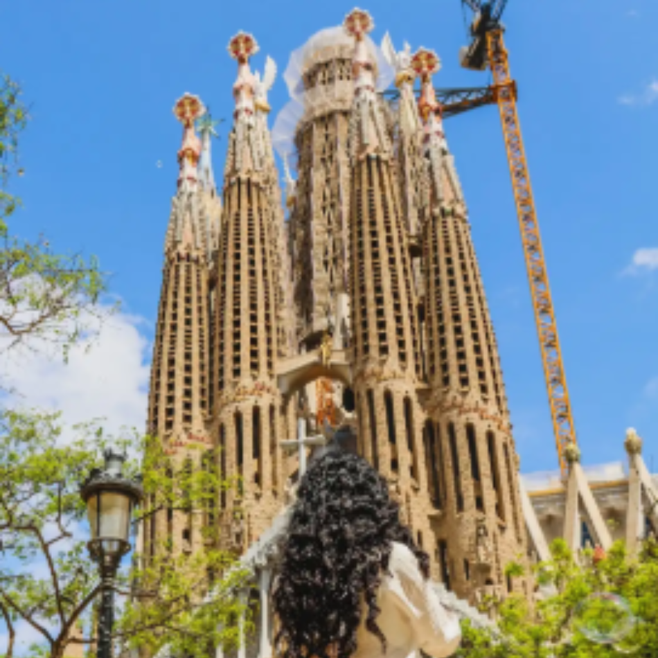 Barcelona's La Sagrada Familia with a woman with dark long hair in front of it. 