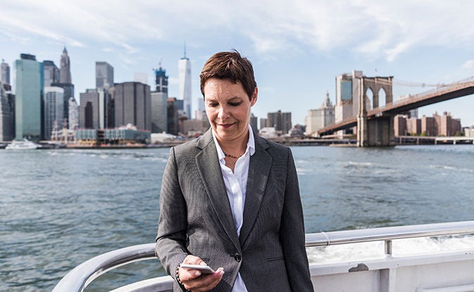 Professional standing by the water using a phone.