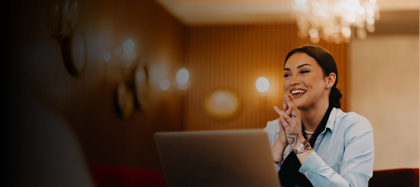 smiling woman clapping at laptop