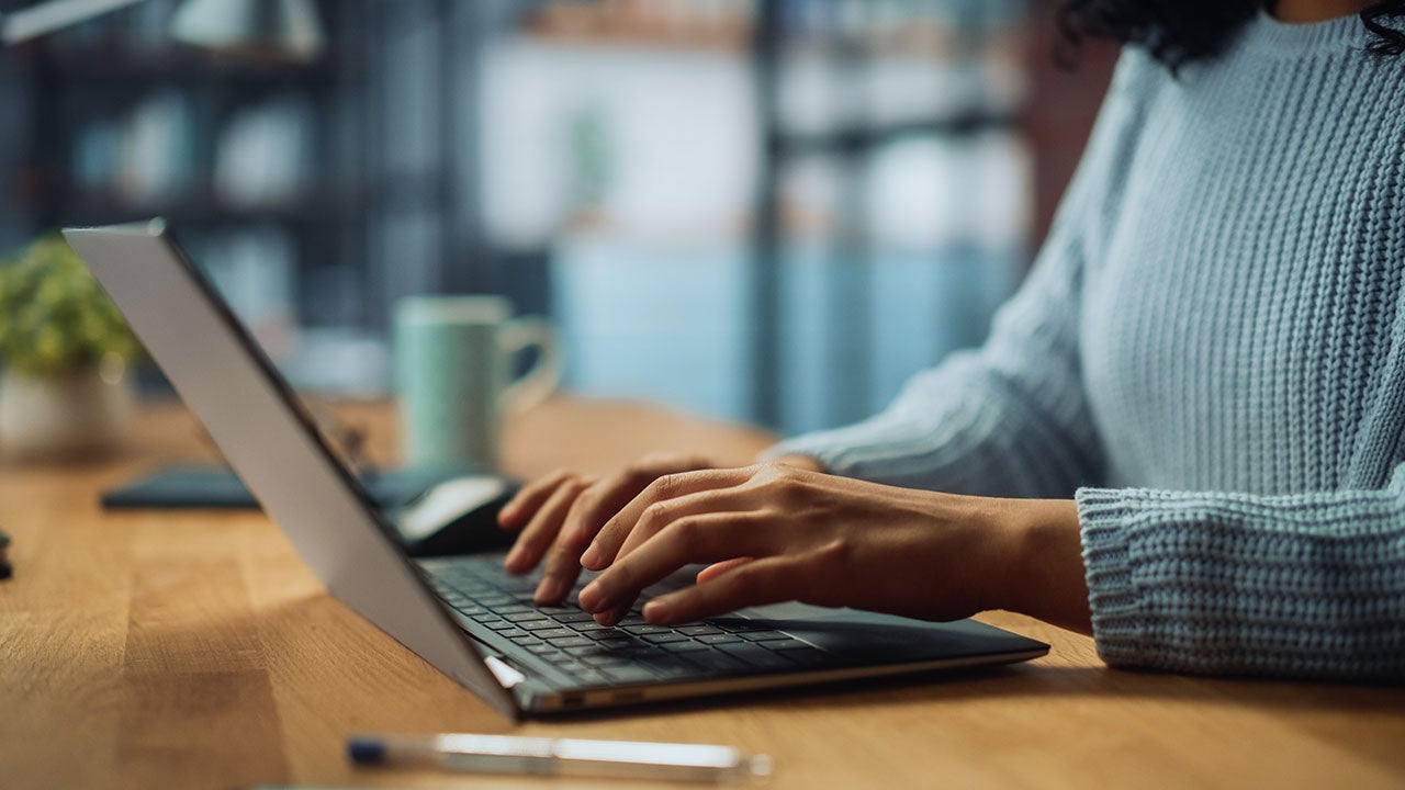 Hands of a female specialist working on laptop.