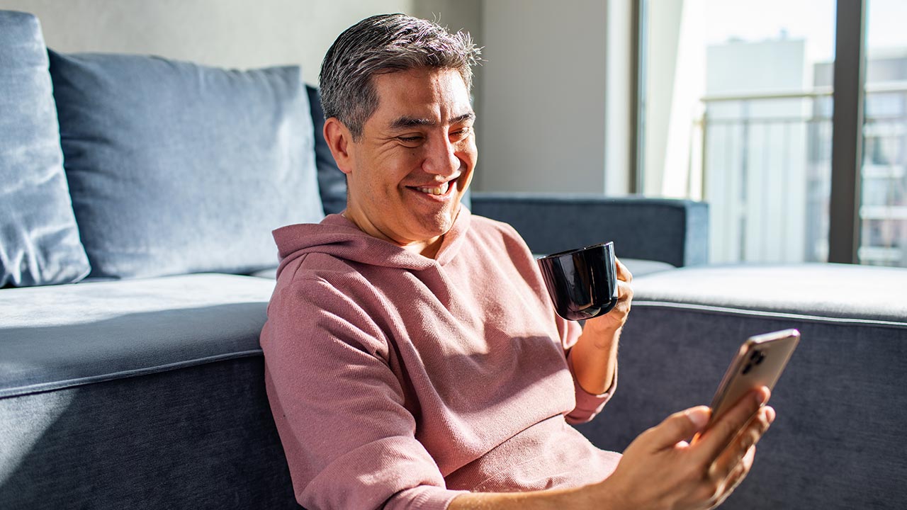 Man on phone drinking coffee smiling