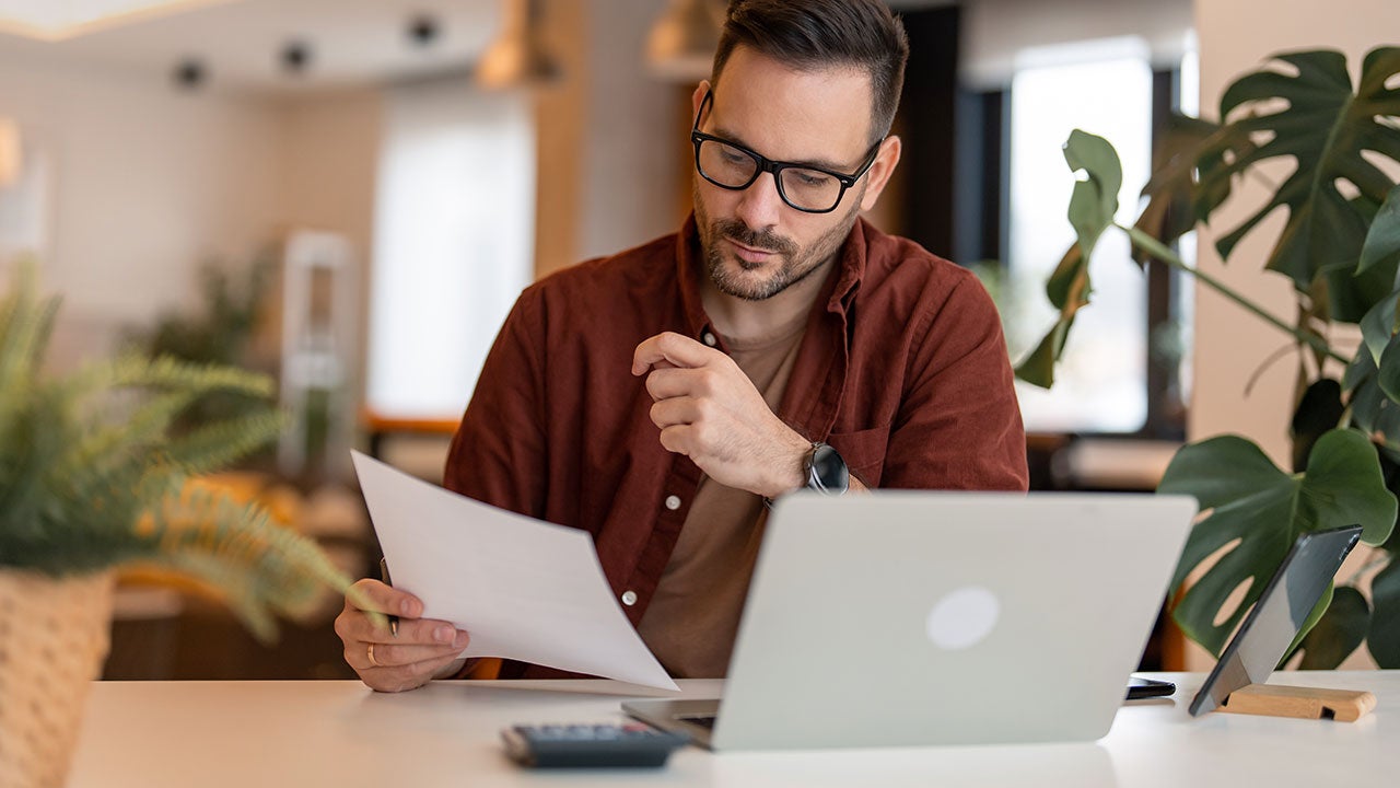 Man sitting at the table in a home office, looking at documents.