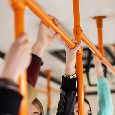 Passengers' hands holding onto stability bars inside a bus.