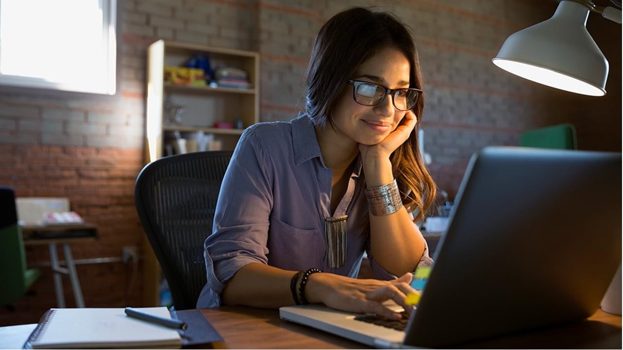 woman smiling while working on a laptop